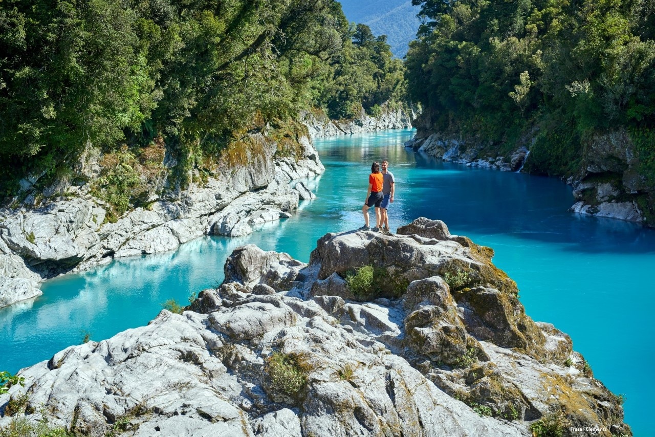 Tourists enjoying the stunning Hokitika Gorge with their rental car.